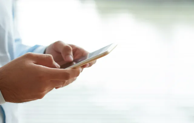 Una persona mirando su celular mientras lo sostiene con las manos